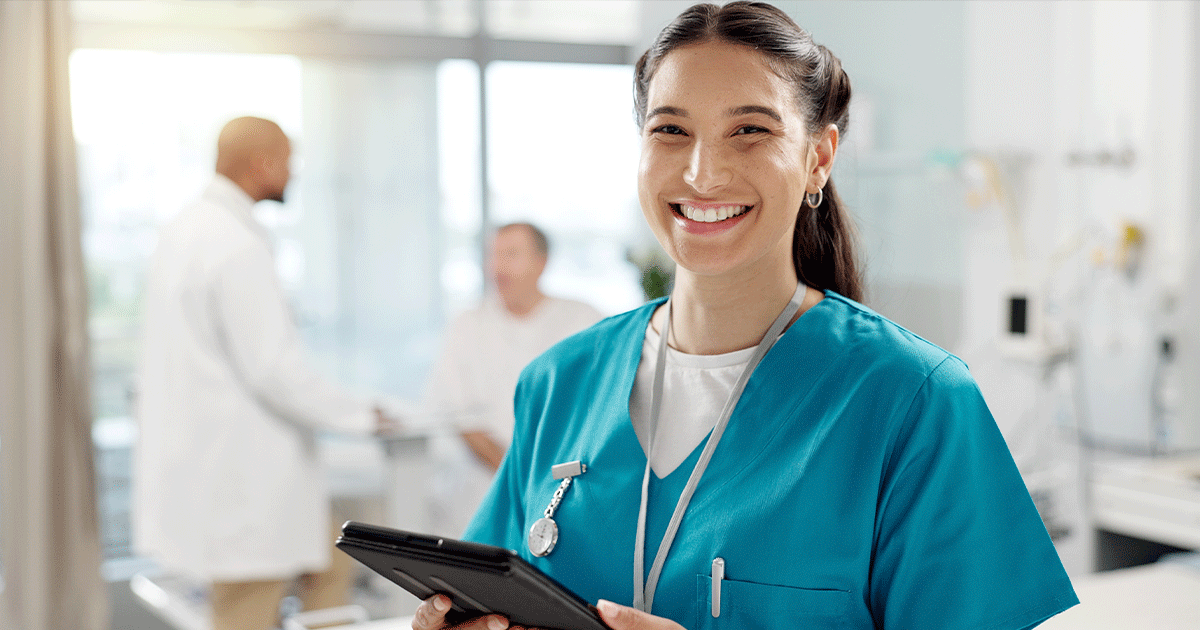 shutterstock_2441465711 Smiling healthcare professional holding a tablet while providing ultrasound and pregnancy care in a medical clinic.